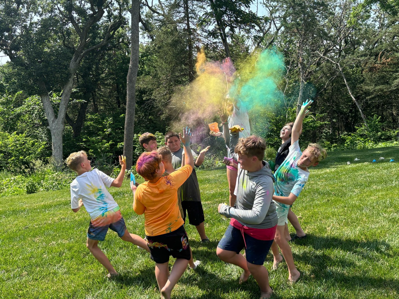 Youth campers tossing colorful powder during an outdoor group activity at Camp Fontanelle